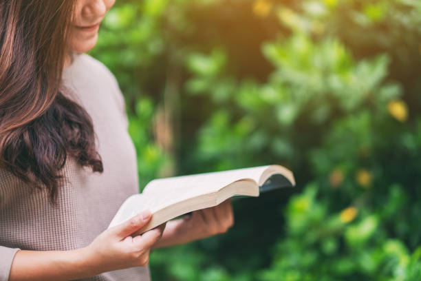 istock woman reading a book while sitting in the park 1184319750