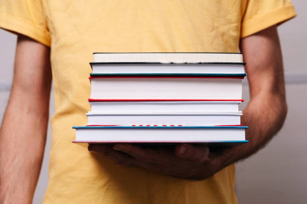 istock a stack of books in the hands of a man 1184319795
