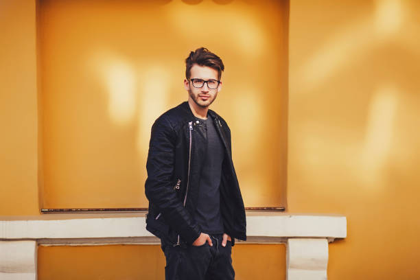 istock Fashionable man in leather jacket posing near colored wall 1184323548