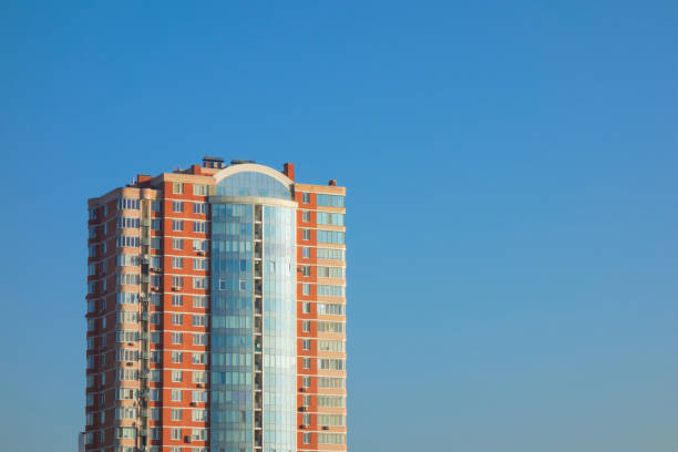 Skyscraper or flat block building on clear blue sky background. Closeup view with copy space. Modern urban architecture landscape