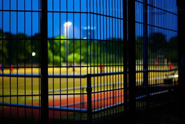 A soccerfield by night behind a fence in Berlin.