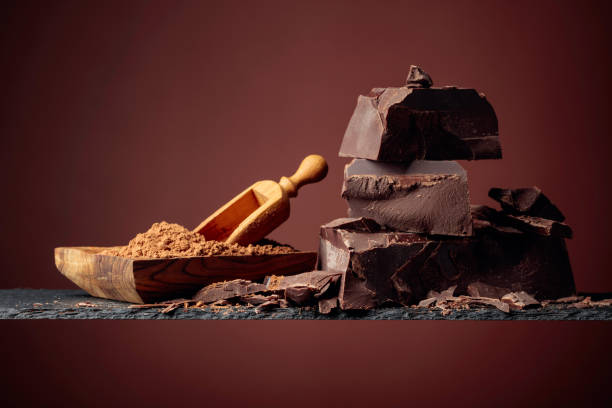 cioccolato nero e piatto di legno con cacao in polvere su sfondo marrone. - chocolate candy bar block cocoa foto e immagini stock