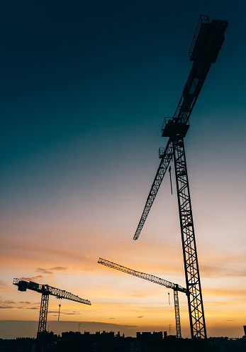 Backlit construction cranes at yard with copy space