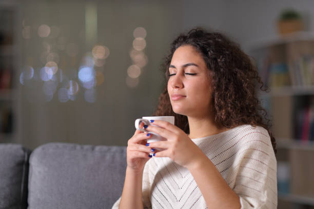 istock Relaxed woman smelling coffee cup in the night 1184339991