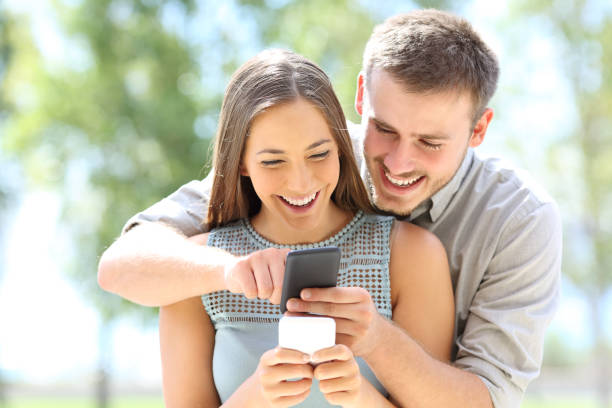 istock Couple sharing smart phone content in a park 1184340264