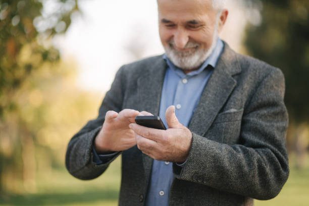 istock Close up of old man with white beard using smartphone outside 1184340670