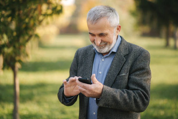 istock Close up of old man with white beard using smartphone outside 1184340711