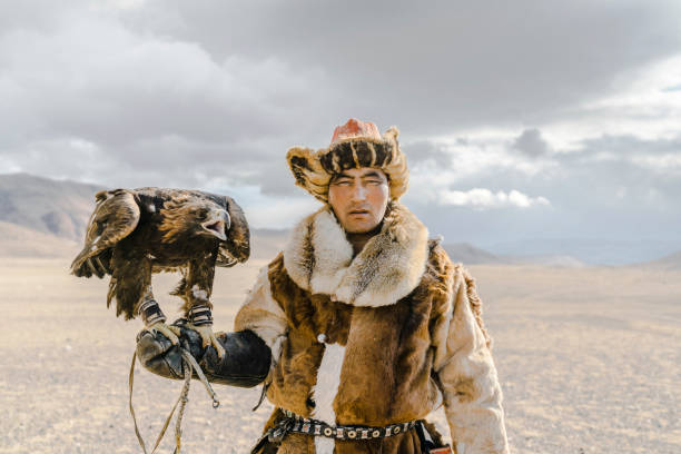 Portrait of eagle hunter standing in desert in Mongolia Portrait of eagle hunter standing in desert in Mongolia independent mongolia stock pictures, royalty-free photos & images