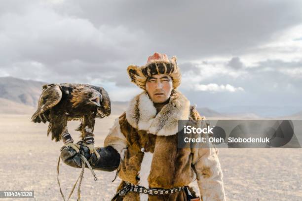 Portrait Of Eagle Hunter Standing In Desert In Mongolia Stock Photo - Download Image Now