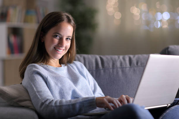 istock Happy woman using laptop looking at camera at home 1184341389