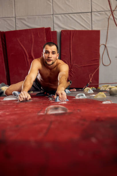 istock Young man climbing on artificial rock, hanging on safety ropes 1184341842