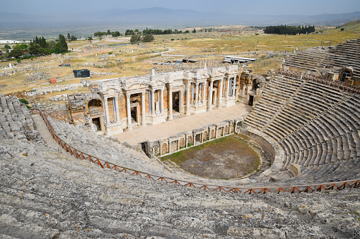 Ancient antique amphitheater in the city of Hierapolis in Turkey. Steps and antique statues with columns in the amphitheater