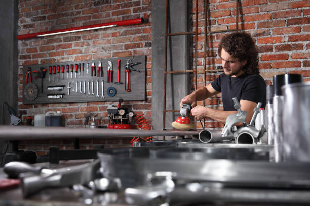 istock man in home workshop garage work metal with wire brush angle grinder machine, repair, brushes and cleaning iron pipe on the workbench full of wrenches, diy concept 1184347979
