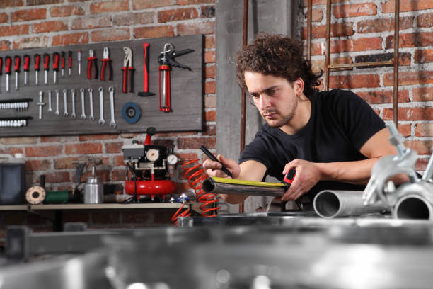 istock man work in home workshop garage measure metal with tape meter, marker iron pipe on the workbench full of wrenches, diy and craft concept 1184347980