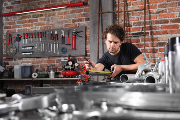 istock man work in home workshop garage measure metal with tape meter, marker iron pipe on the workbench full of wrenches, diy and craft concept 1184347982