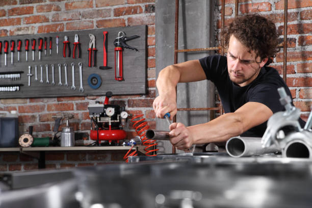 istock man work in home workshop garage with steel file rasp, filing metal pipe on the workbench full of wrenches, diy and craft concept 1184347984