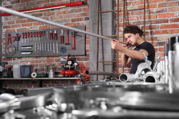 istock man work in home workshop garage checks the horizontal surface of metal pipe on the workbench full of wrenches, diy and craft concept 1184347992