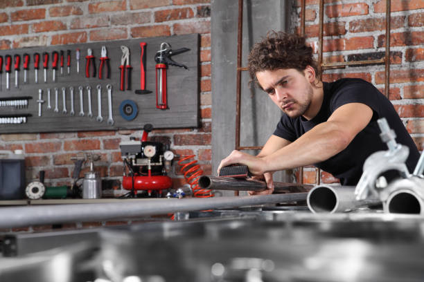 istock man work in home workshop garage with sandpaper sanding surface of metal pipe on the workbench full of wrenches, diy and craft concept 1184347993