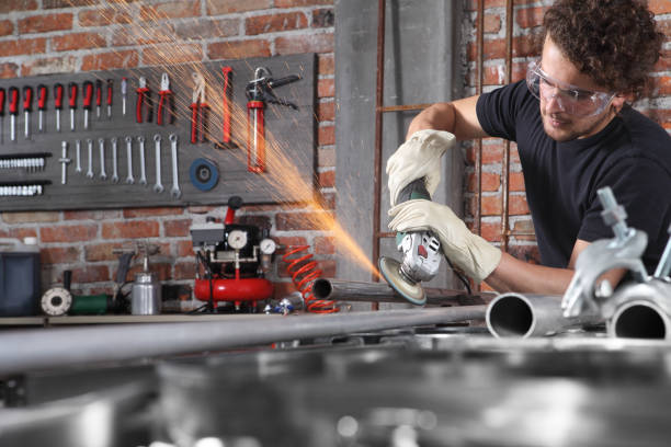 man work in home workshop garage with angle grinder, goggles and construction gloves, grinder metal makes sparks, diy and craft concept