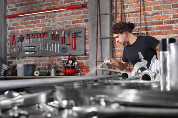 istock man work in home workshop garage with spray can paint metal pipe on the workbench full of wrenches, diy and craft concept 1184347996
