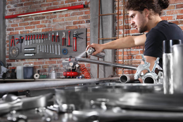 istock man work in home workshop garage with spray can paint metal pipe on the workbench full of wrenches, diy and craft concept 1184348006