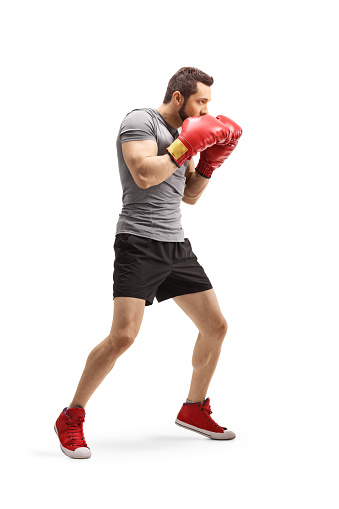 Full length shot of a boxer with red boxing gloves in guard position isolated on white background