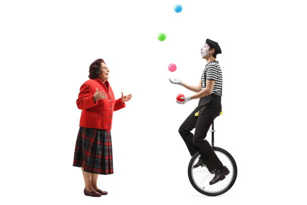 istock Elderly lady looking at a mime juggling on a unicycle 1184349760