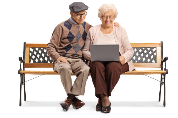 istock Happy senior man and woman on a bench with a laptop computer 1184349792