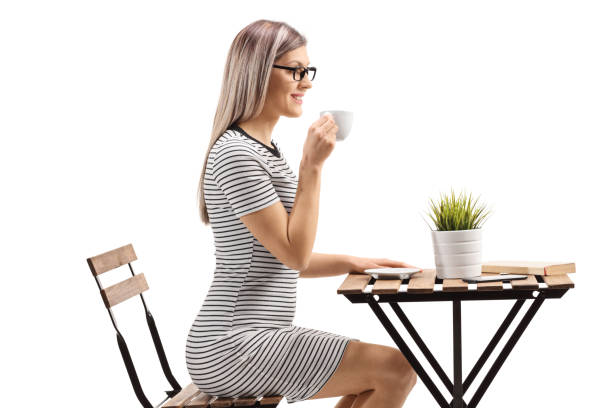 istock Young blond woman drinking coffee and sitting at a table 1184350424
