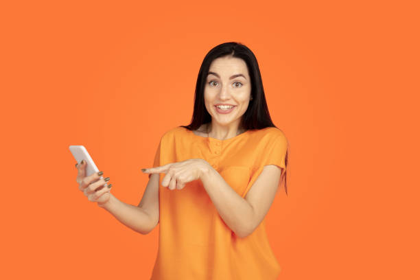 istock Caucasian young woman's portrait on orange background 1184354236