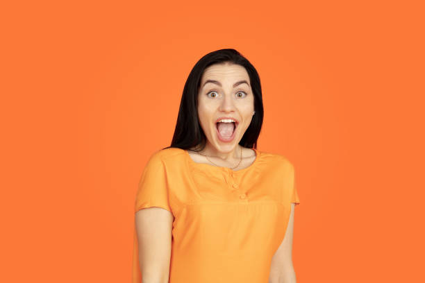 istock Caucasian young woman's portrait on orange background 1184354271