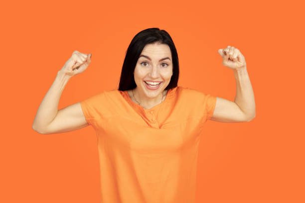 istock Caucasian young woman's portrait on orange background 1184354284