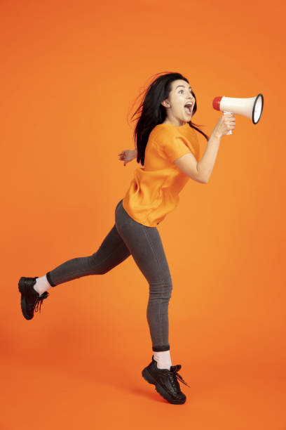 istock Caucasian young woman's portrait on orange background 1184354329