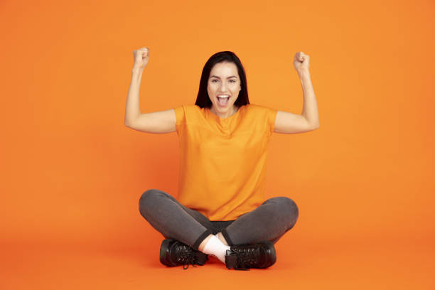 istock Caucasian young woman's portrait on orange background 1184354335