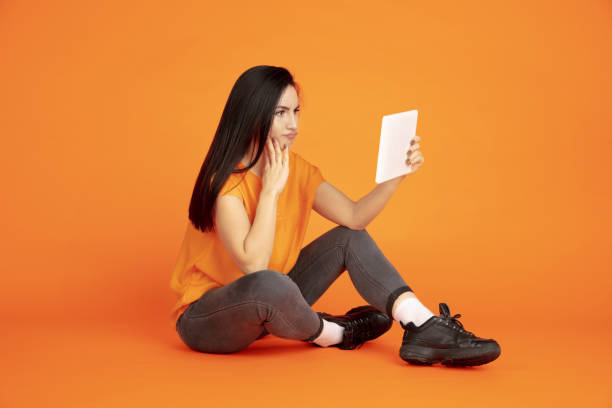 istock Caucasian young woman's portrait on orange background 1184354344
