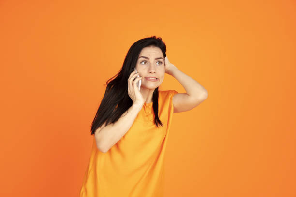 istock Caucasian young woman's portrait on orange background 1184354360