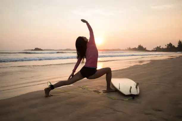 Photo of Woman surfer warming up on sunset beach