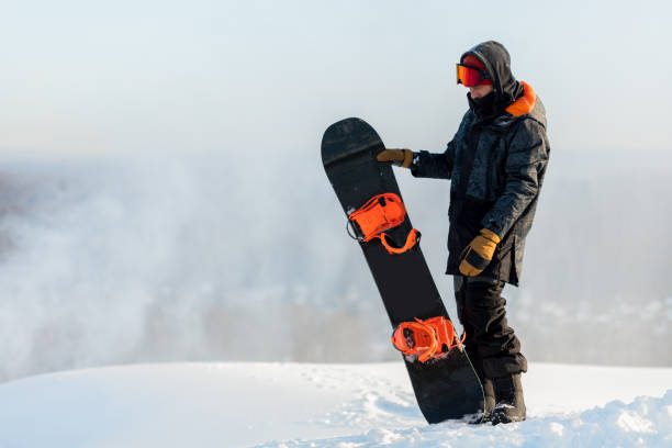 istock sporty man with snowboard standing on the hill 1184359786