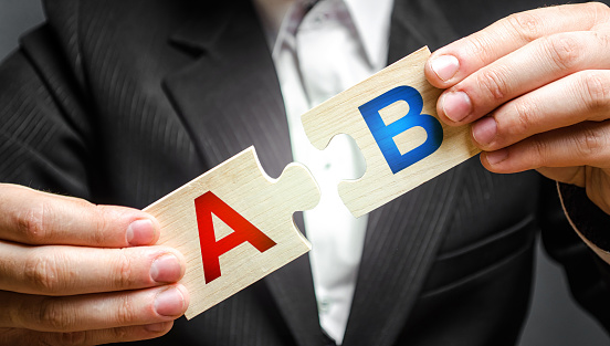 A man connects puzzles with the letters A and B. A/B test marketing research method. multivariate testing. Improving products and services based on statistics and observations. Marketer
