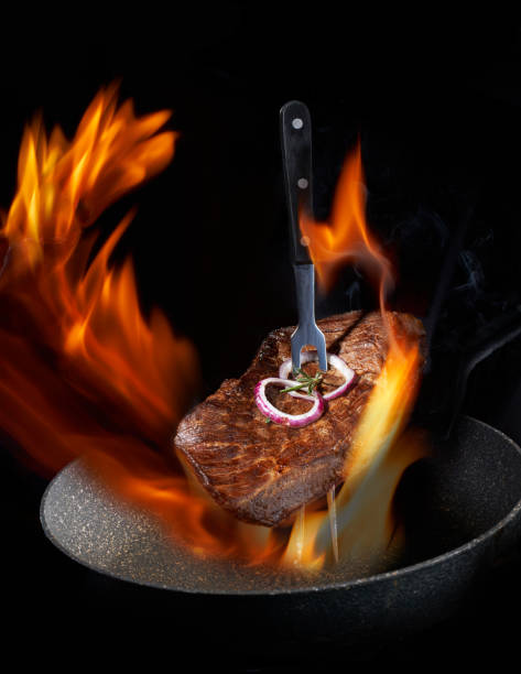 istock Flying hot grilled meat steak beef with Rosemary  on fork with open fire. Free space for text design or logotype menu restaurant.  Concept: Restaurant and hotel service. 1184361462