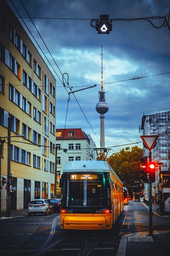 Yellow electric tram at Berlin, Germany. Cloudy sky and television Tower background.