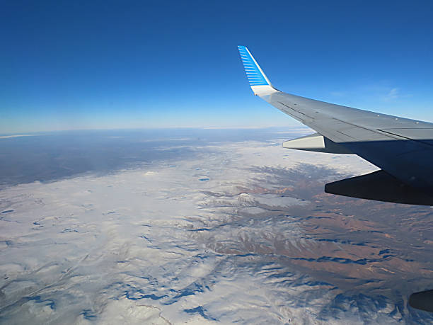Beautiful Aerial View Through the Aircraft Window at the Cloudy Sky and Area Covered with Snow in Argentina.