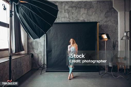 istock Young stylish woman with crossed legs and hands on the pockets posing 1184365339
