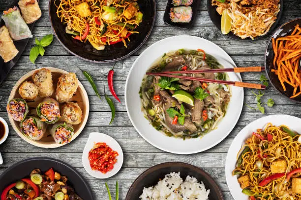 Top view composition of various Asian food in bowls served on wooden table
