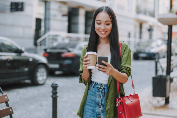 istock Happy Asian lady is walking with coffee 1184369002