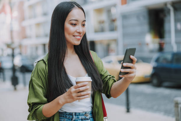 istock Happy young lady is walking with smartphone 1184369051