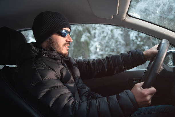 istock Driver driving in winter clothes. Side view. Winter outside. 1184370393