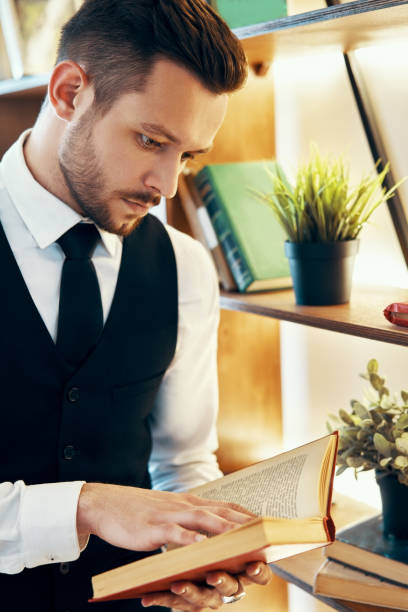 istock Handsome young man in elegant suit reading a book in modern luxury interior 1184370858
