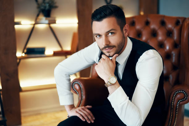 istock Handsome young man sitting and posing in armchair in modern luxury interior 1184370865