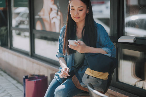istock Happy Asian female is looking on mobile phone 1184371543